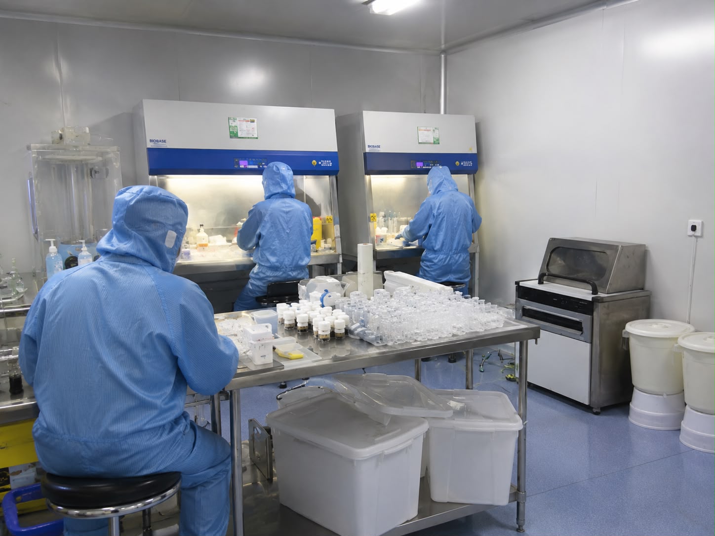 Technicians filling vials under laminar flow biosafety cabinets